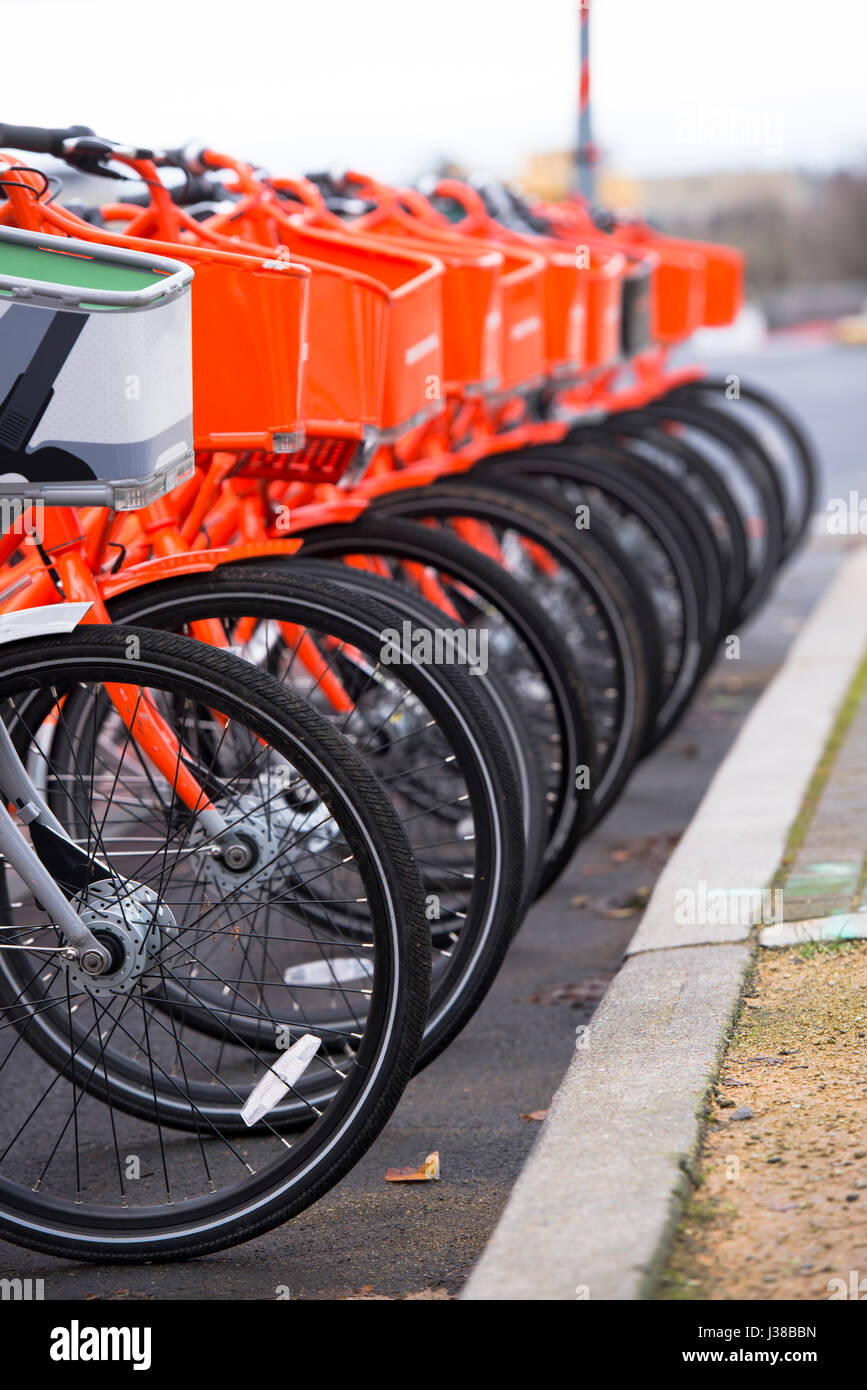 Vélos orange avec des paniers à l'avant et roues polies pour les utiliser et bordée d'un séjour vélo gris pas symboliques susceptibles d'autres se Banque D'Images