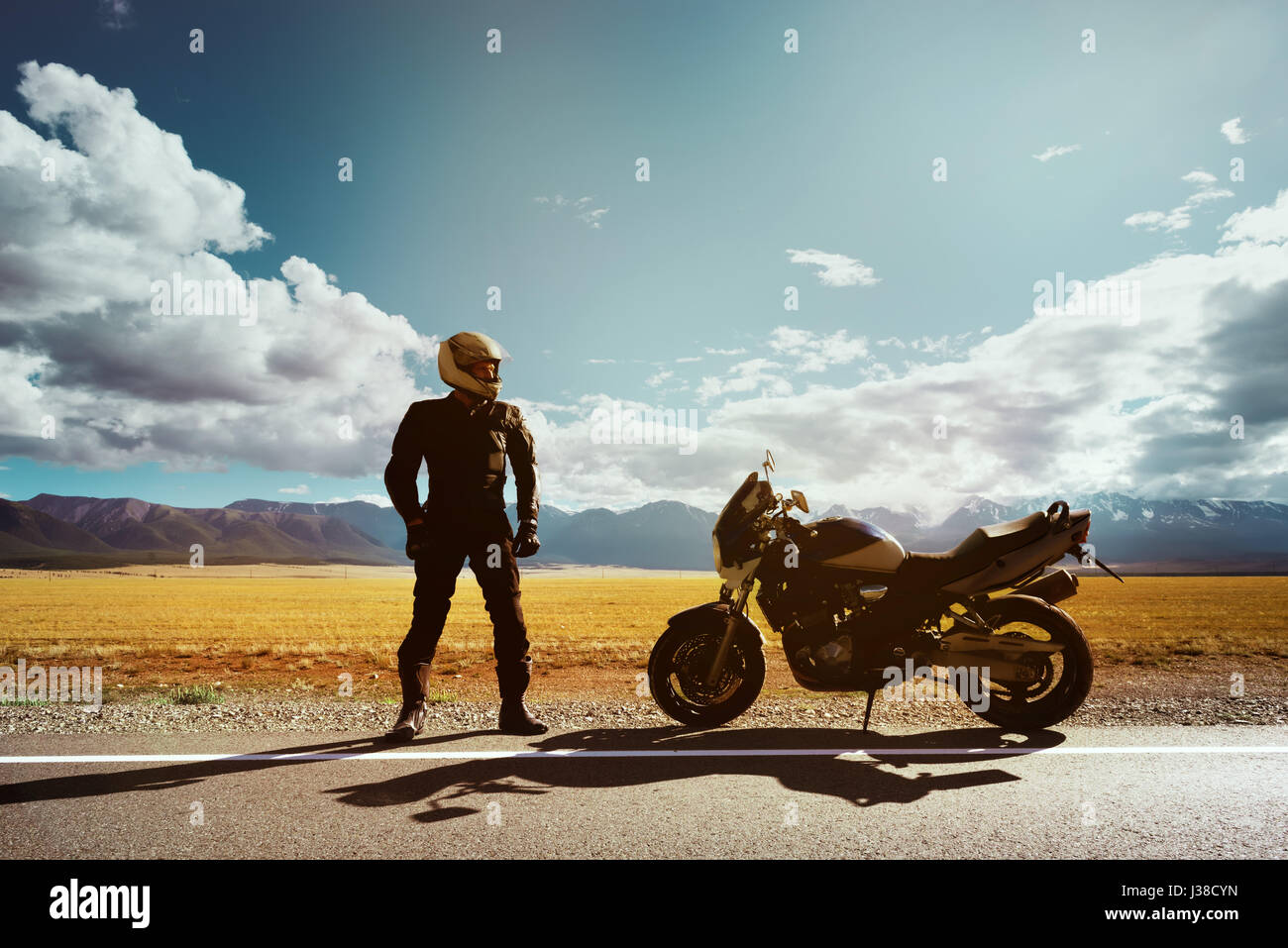 Moto avec motard se dresse sur la route sur fond de montagnes. Un espace réservé au texte Banque D'Images