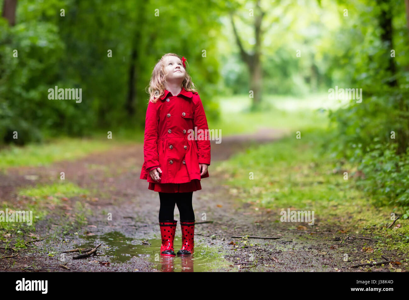 Petite fille jouant dans le parc de l'été pluvieux. Enfant avec parapluie  Coccinelle rouge manteau imperméable, bottes et sauter en flaque de boue et  sous la pluie. Kid walkin Photo Stock -