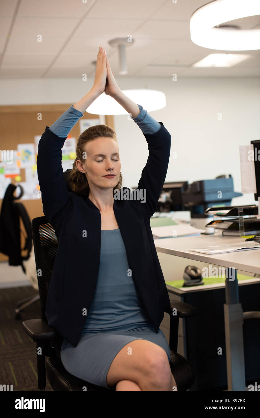 Businesswoman meditating while sitting on chair at office Banque D'Images