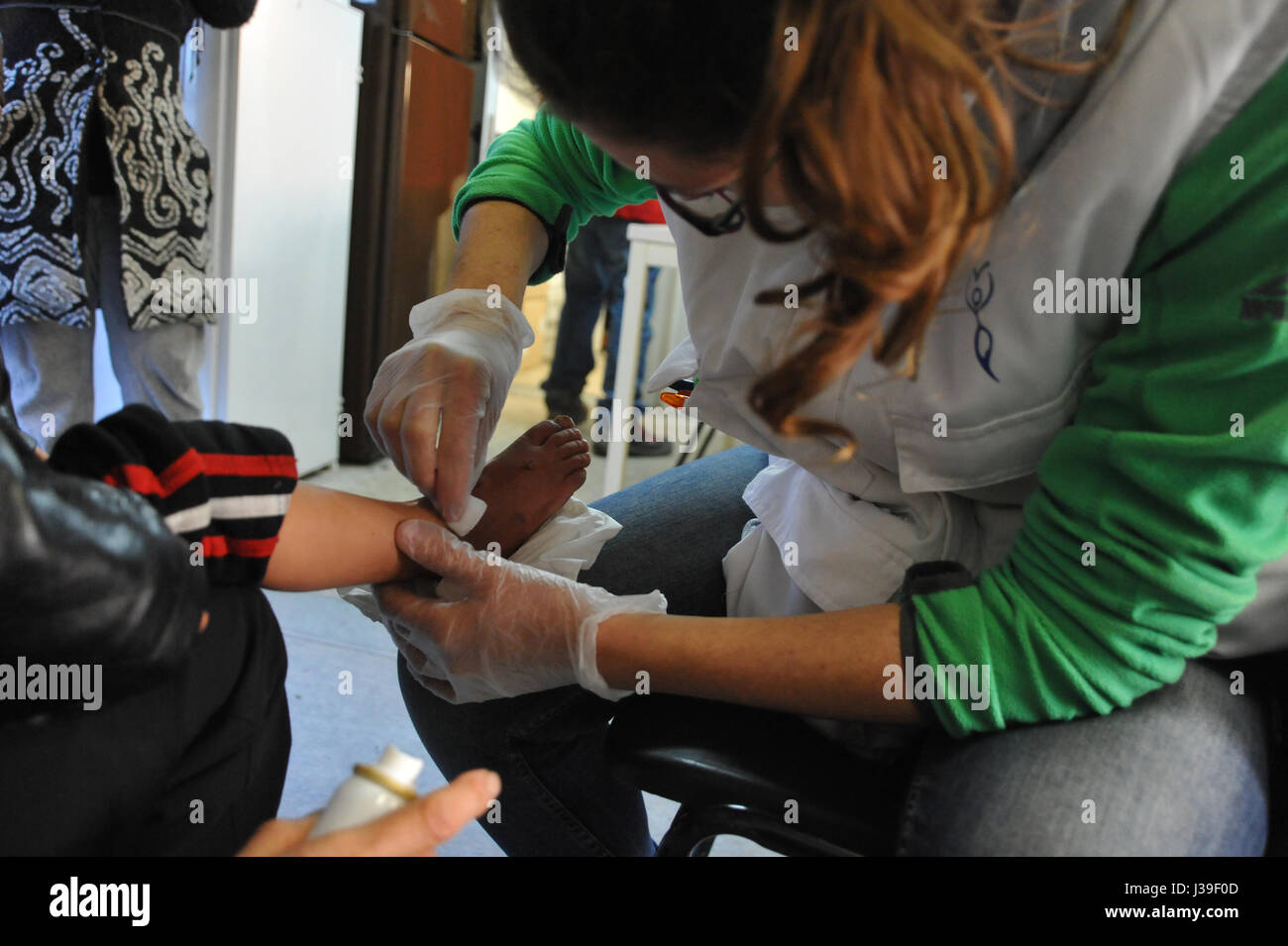 Reportage sur les bénévoles avec l'organisme de bienfaisance, les gynécologues sans frontières qui travaillent dans les camps de réfugiés près de Calais dans le nord de la france. sage-femme traiter le pied d'un enfant. Banque D'Images