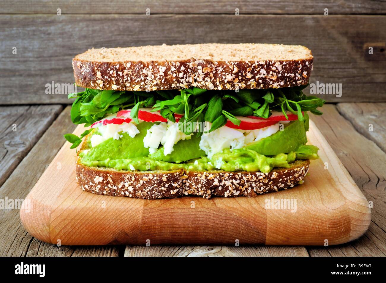 Sandwich Superfood avec de l'avocat, les blancs d'œufs, de radis et de pousses de pois sur pain de grains entiers contre un arrière-plan en bois rustique Banque D'Images