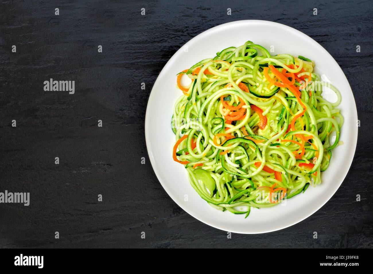 Bas carb les courgettes plat de nouilles avec des carottes et de la chaux sur fond d'ardoise sombre, overhead view Banque D'Images