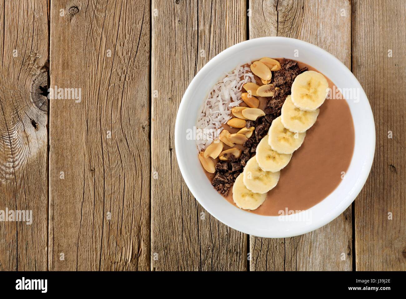 Le beurre d'arachides, bananes smoothie chocolat bol sur un fond de bois rustique Banque D'Images