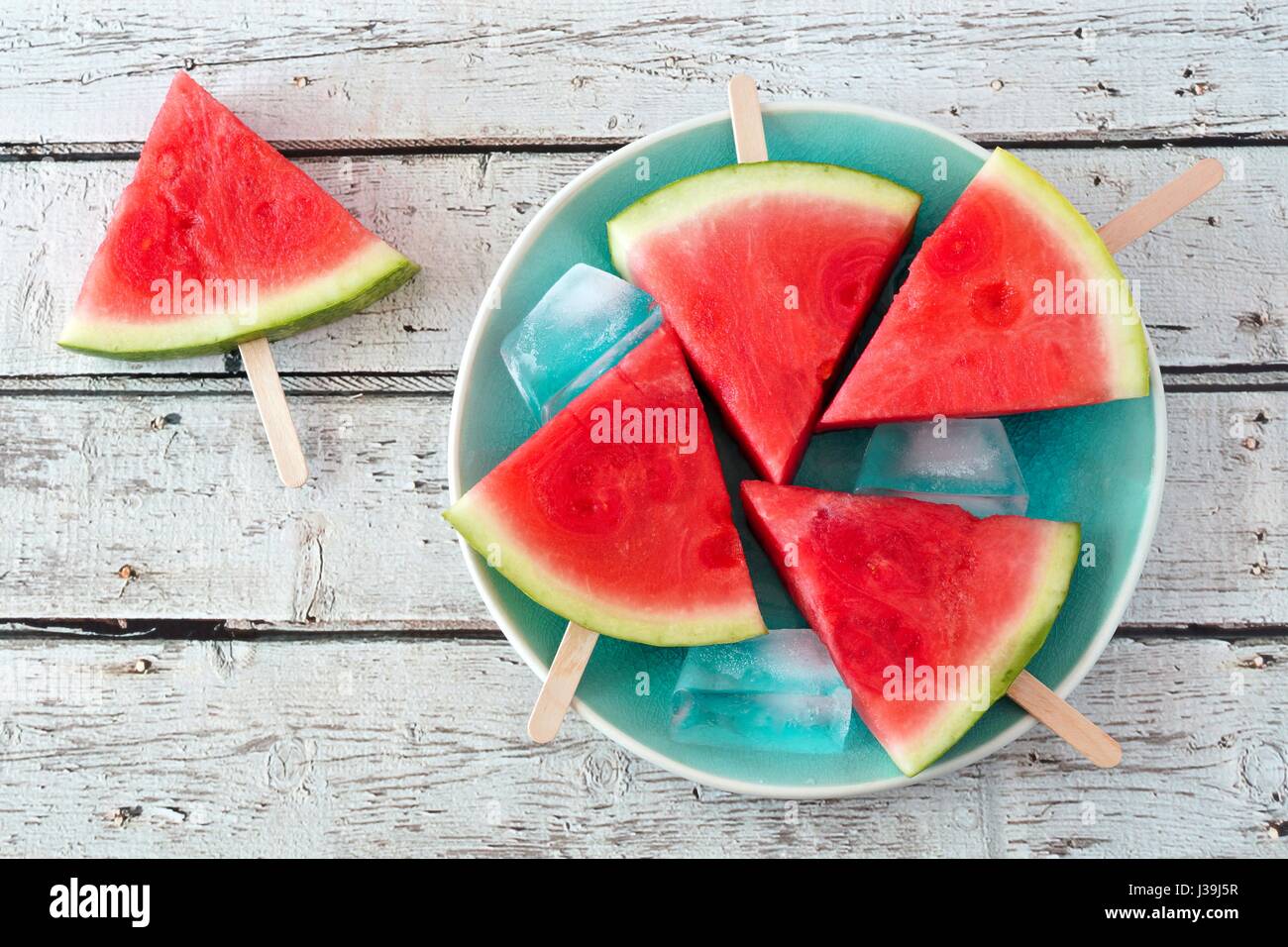 Watermelon slice les sucettes glacées sur une plaque bleue vintage et fond en bois rustique Banque D'Images