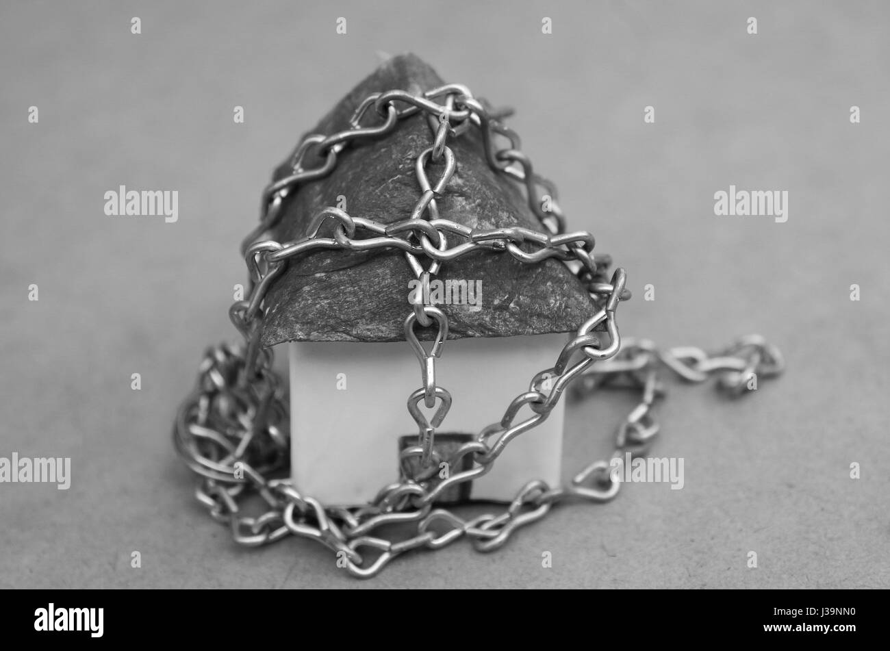 Une belle chaîne enroulée autour d'un petit modèle maison faite de papier en noir et blanc Banque D'Images