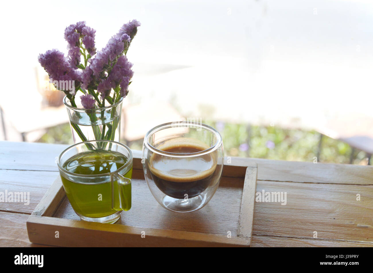 Café Expresso chaud dans le plateau en bois et fleurs Statice violet color dans le verre. Banque D'Images