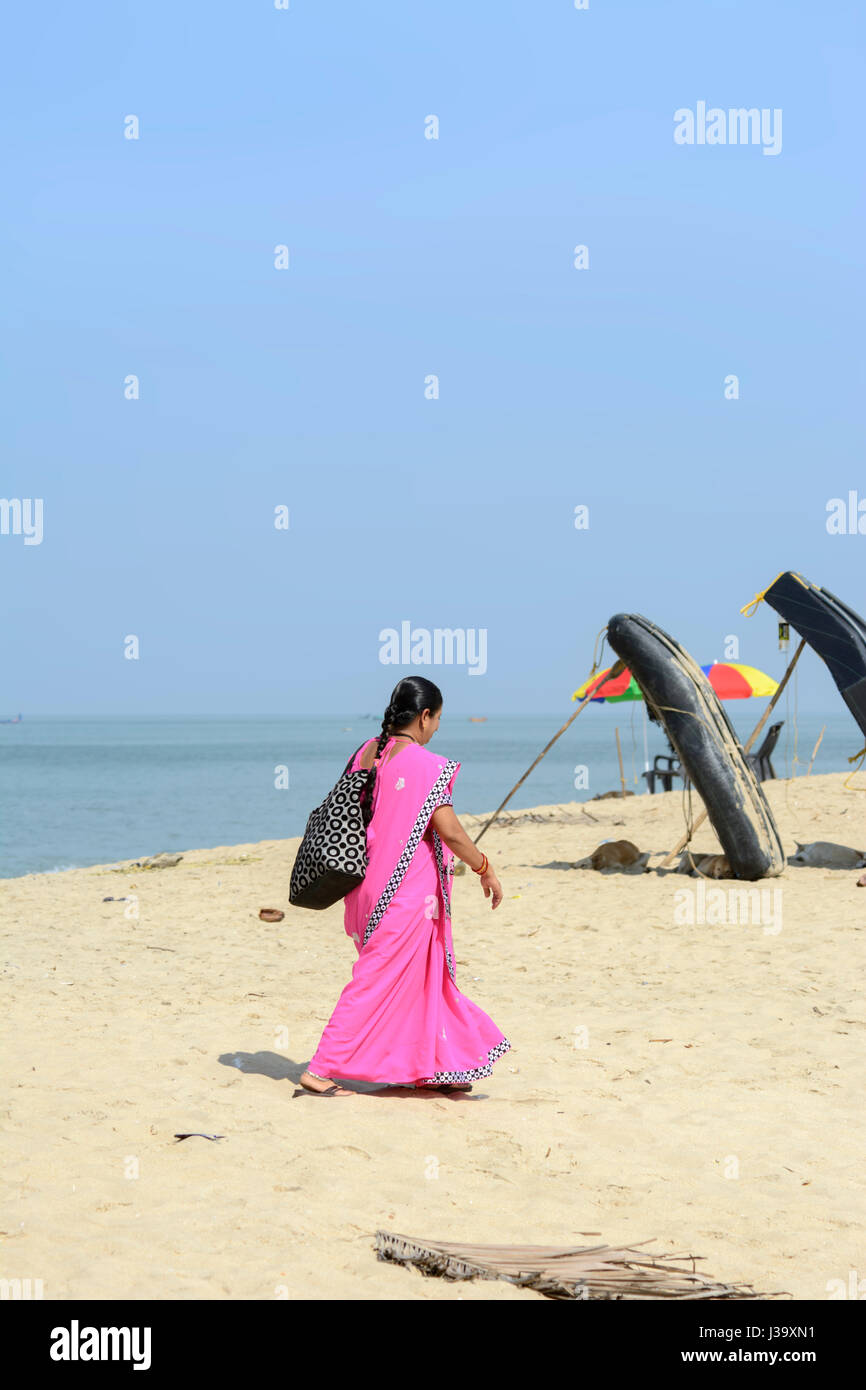 Une femme portant un Keralan sari rose marche à travers le sable à Marari Beach, Mararikulam, Alleppey (Alappuzha District), Kerala, Inde du Sud, en Asie du Sud Banque D'Images
