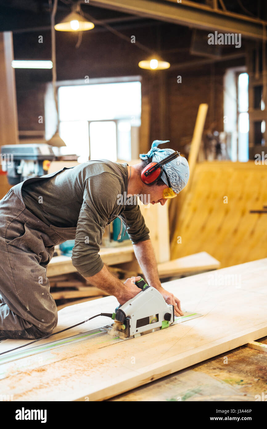 Homme couper du bois en atelier de menuiserie Banque D'Images