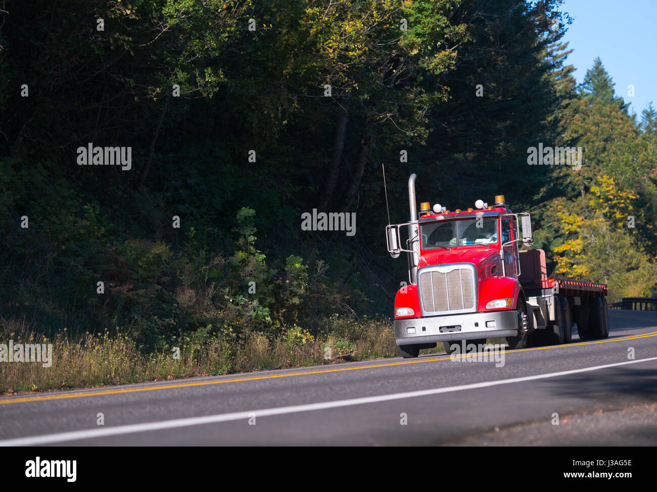 Cabine de jour moderne rouge semi truck gros camion calandre chromée avec remorque à plateau et aller tout droit par multy-line pour ramassage de fret rapide local deli Banque D'Images