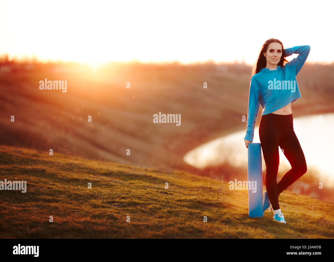 Femme de remise en forme avec des tapis de yoga dans la nature au coucher du soleil Banque D'Images