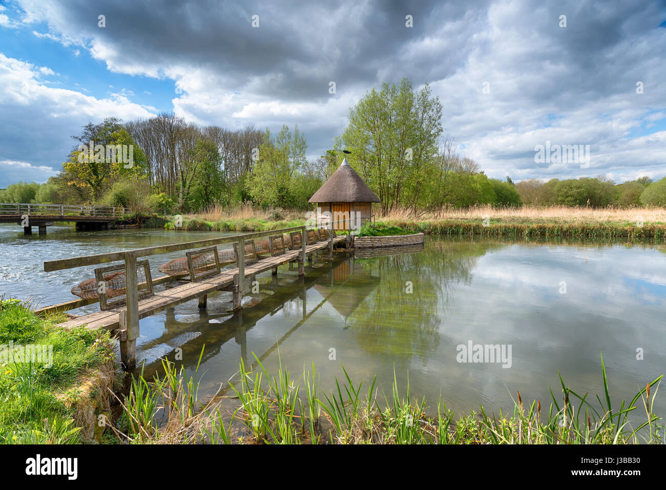 Une cabane de pêcheur de chaume et les pièges de l'anguille sur la rivière Test à Longstock dans Hampshire Banque D'Images