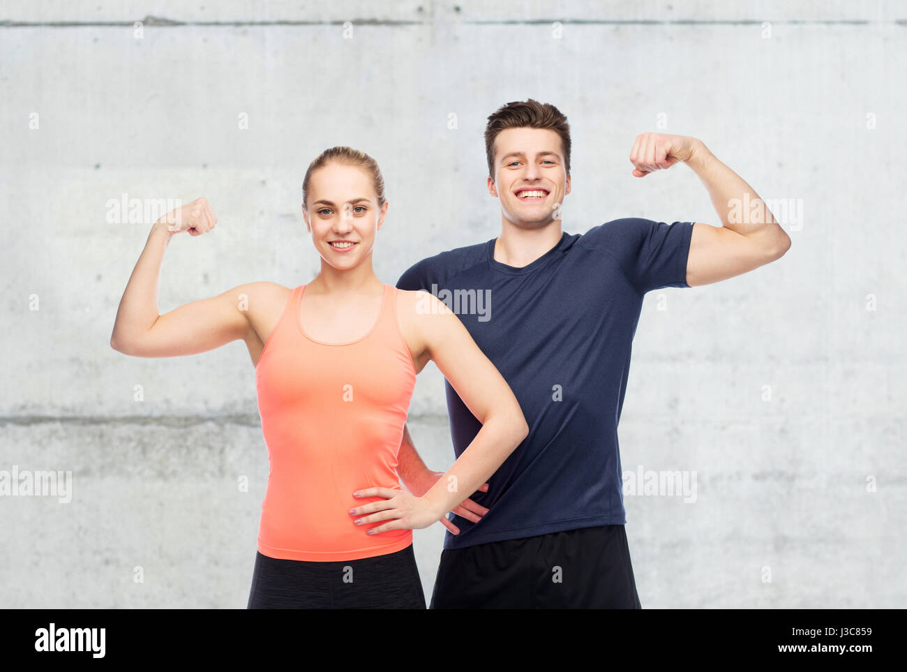 Heureux l'homme et de la femme sportive montrant la puissance de biceps Banque D'Images