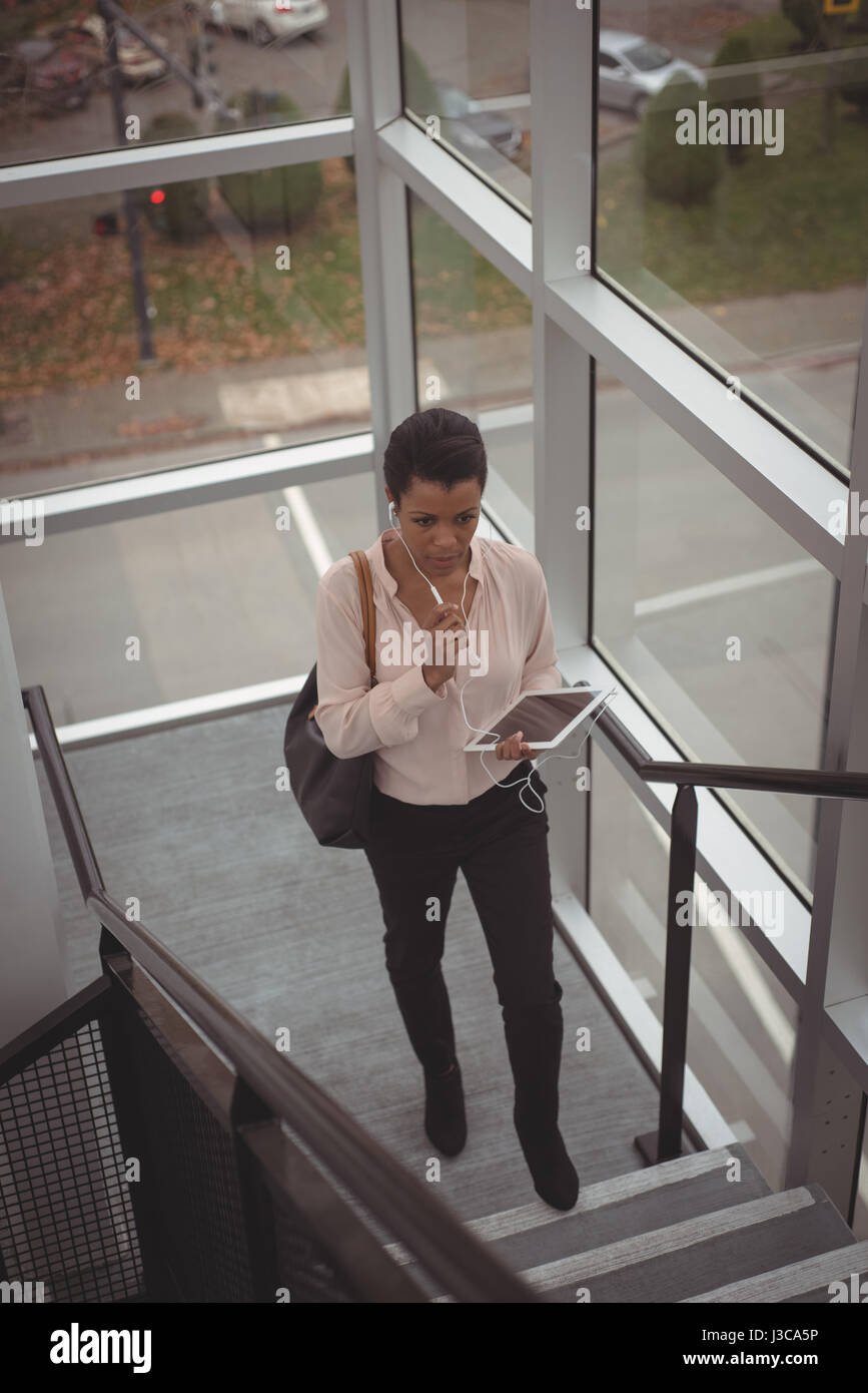 Businesswoman dispositif mains libres tout en marchant à l'escalier Banque D'Images