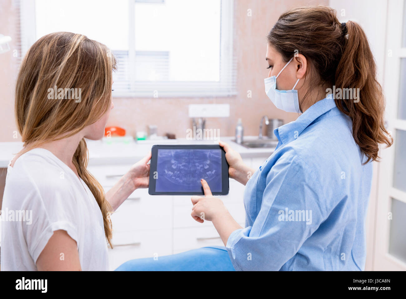 Dentist showing teeht x-ray sur tablet pc ordinateur pour femme patient au cabinet dentaire Banque D'Images