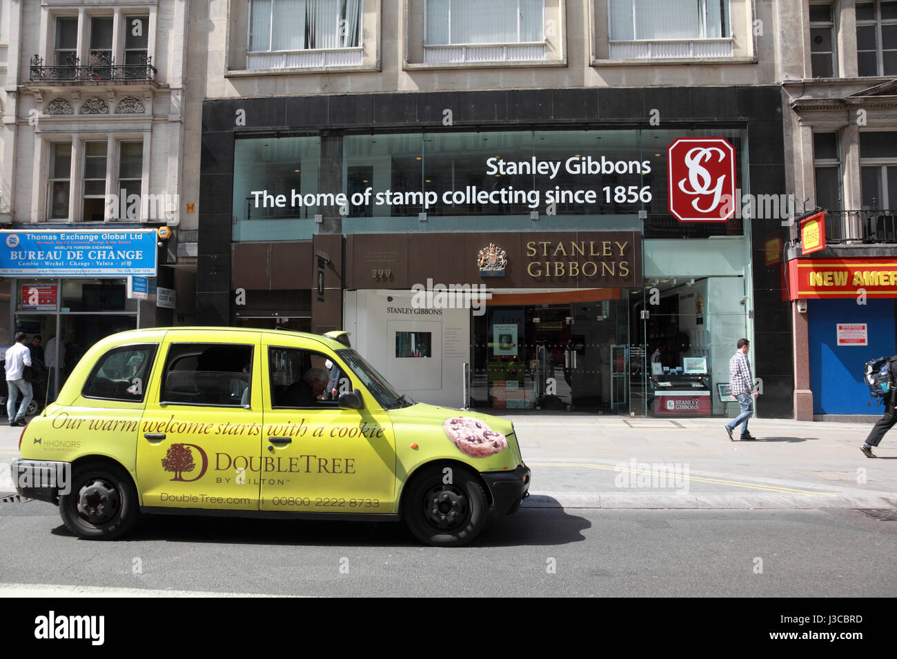 Un taxi à l'extérieur des hôtels DoubleTree Hilton publicité Stanley Gibbons sur le Strand, London Banque D'Images