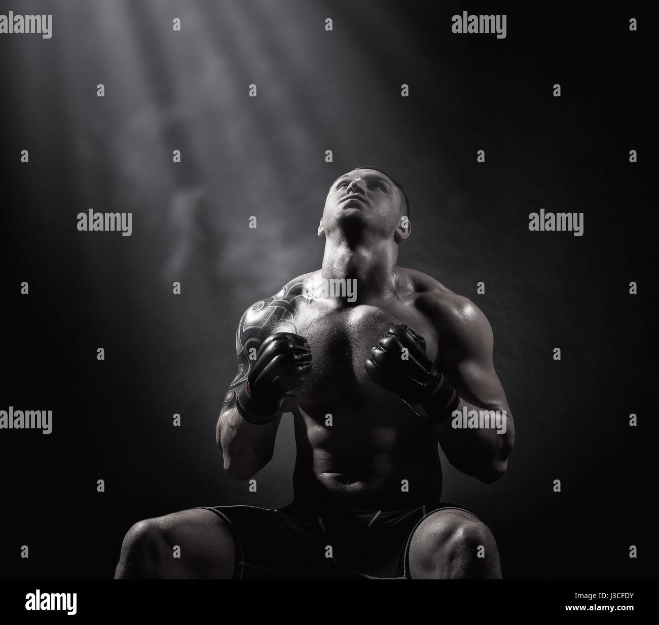 Boxer avec des gants de boxe s'assied avant combat sur un fond noir. Concept de boxe Banque D'Images
