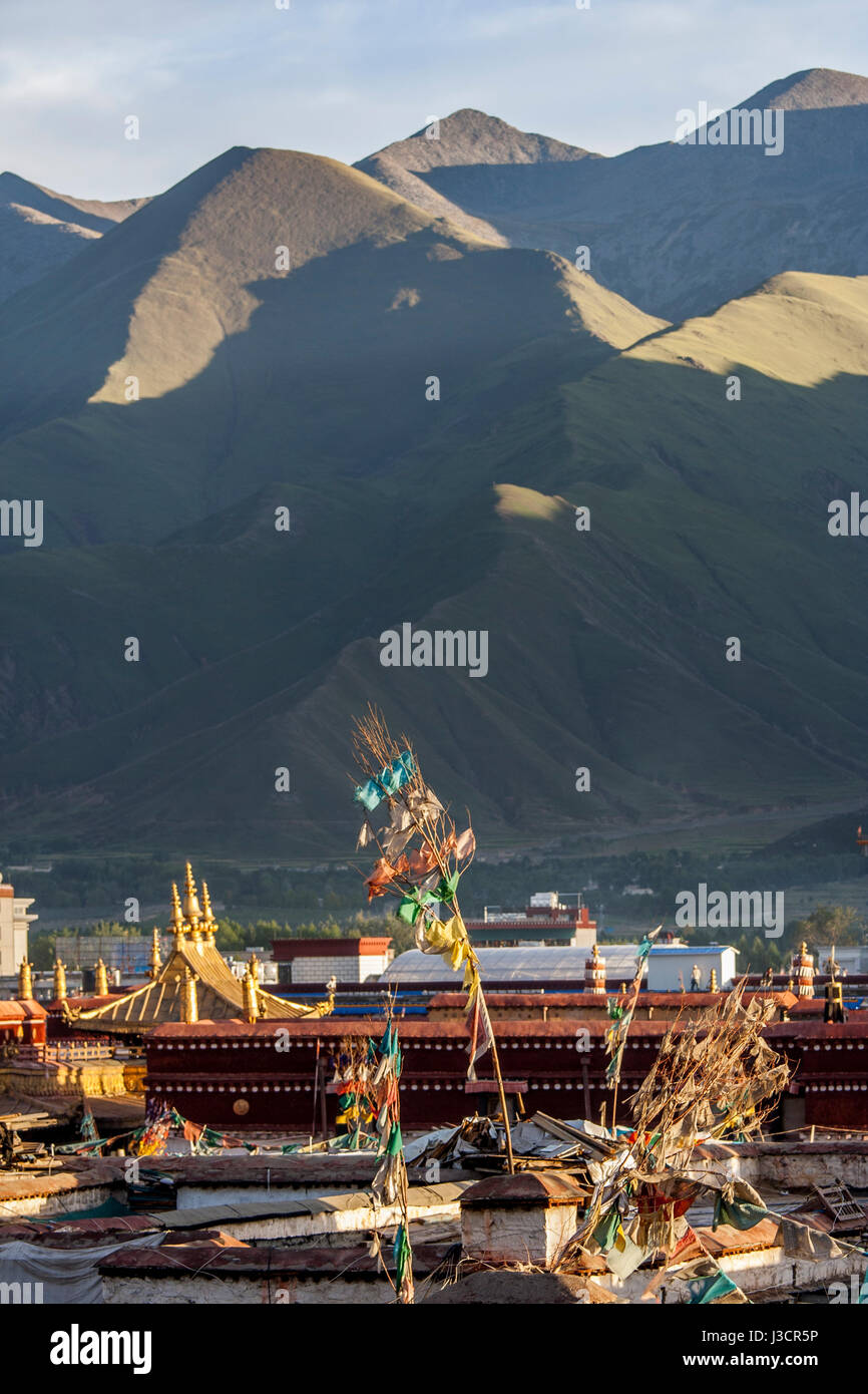 Les pinacles d'or de temple du Jokhang parmi beaucoup de toits de maisons à Lhassa et en fin d'après-midi au soleil en montagne backgroud Banque D'Images