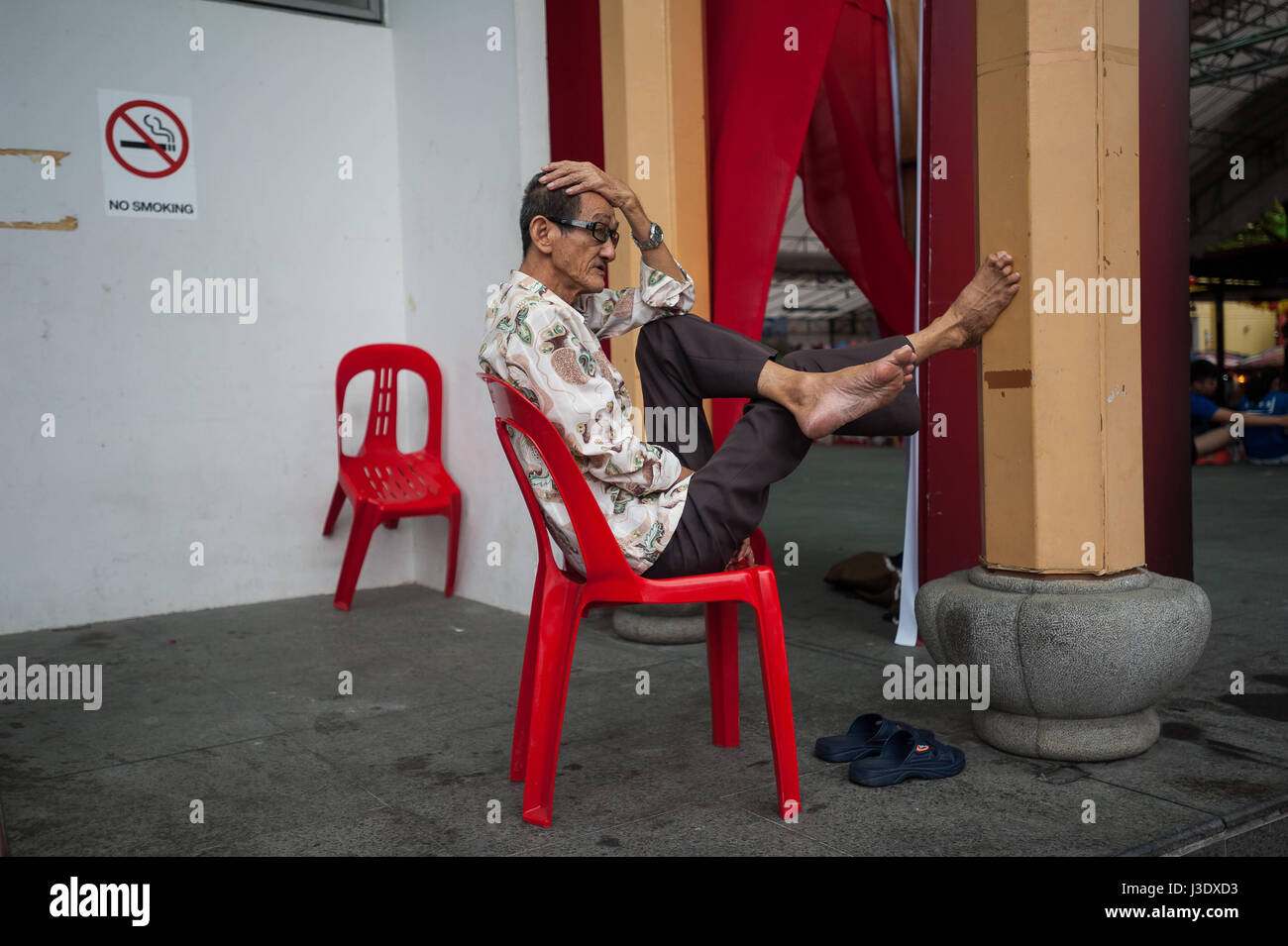 Singapour, République de Singapour, un homme se détend sur une chaise plastc Banque D'Images