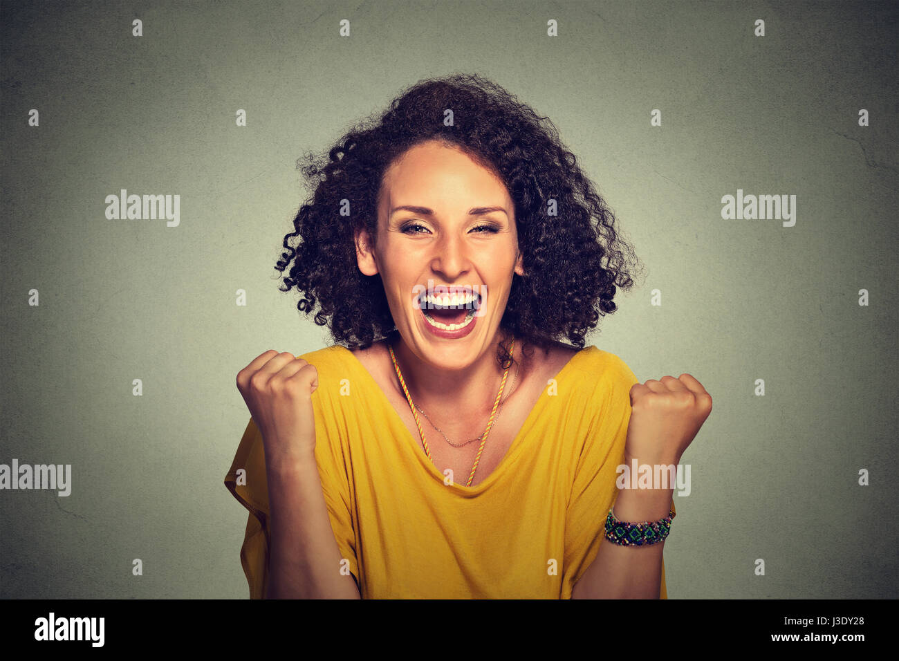 Happy woman poings pompage exulte de joie célèbre son succès sur fond gris Banque D'Images