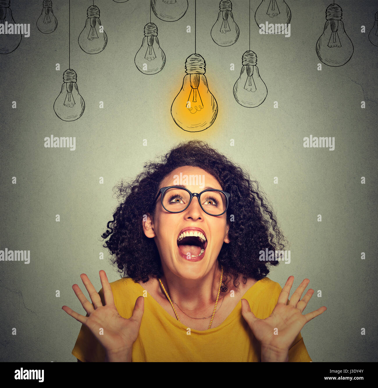 Super happy portrait femme excité dans les verres à la recherche jusqu'à l'idée lumineuse au-dessus de la tête de lampe isolé sur fond de mur gris Banque D'Images