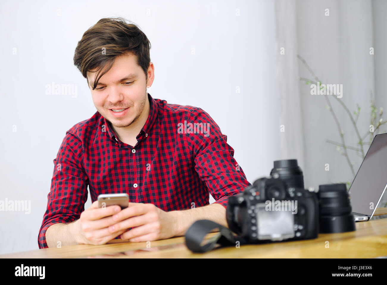 L'homme est de la lecture d'un message sur un smartphone assis à une table dans l'office Banque D'Images