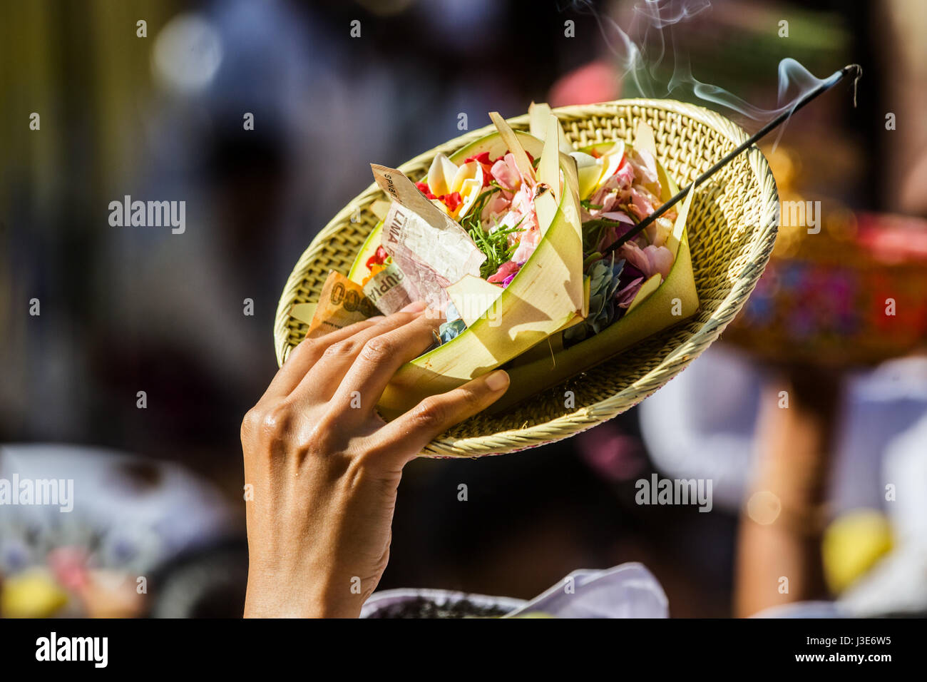 Canang Sari Bali offrandes religieuses et d'encens par un holding hindoue haut au-dessus de l'objet la foule lors d'une cérémonie religieuse Banque D'Images