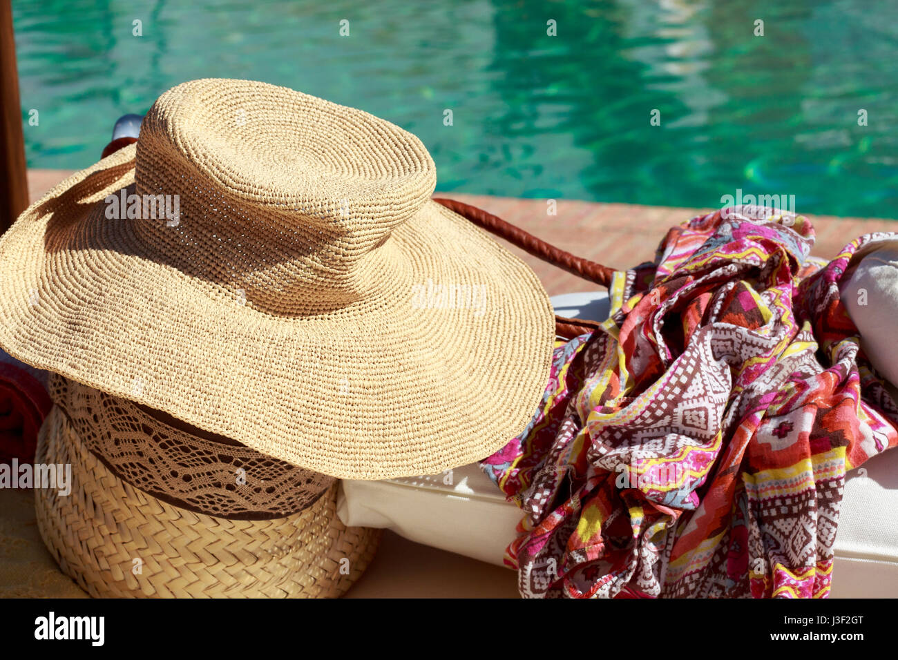 Chapeau de soleil et paréos en face d'une piscine Banque D'Images