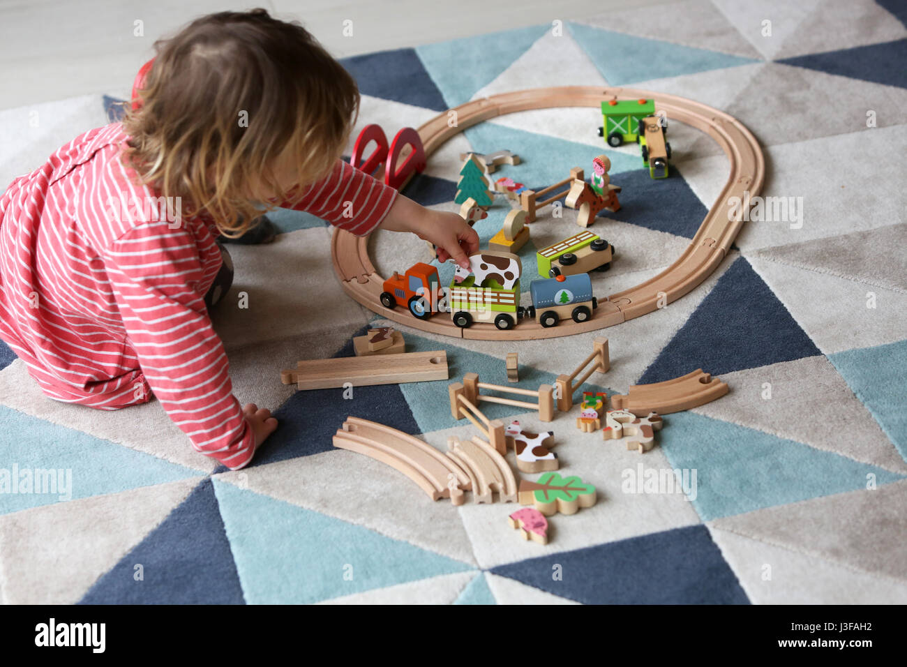 Une jeune fillette de deux ans sur la photo en jouant avec des jouets en bois dans son salon à son domicile à Sussex, UK. Banque D'Images