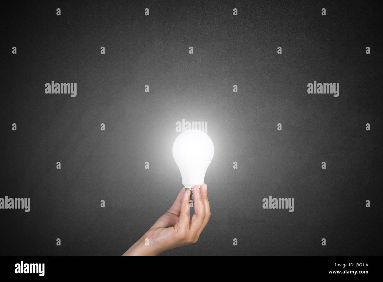Woman hand holding Light bulb in front of blackboard Banque D'Images