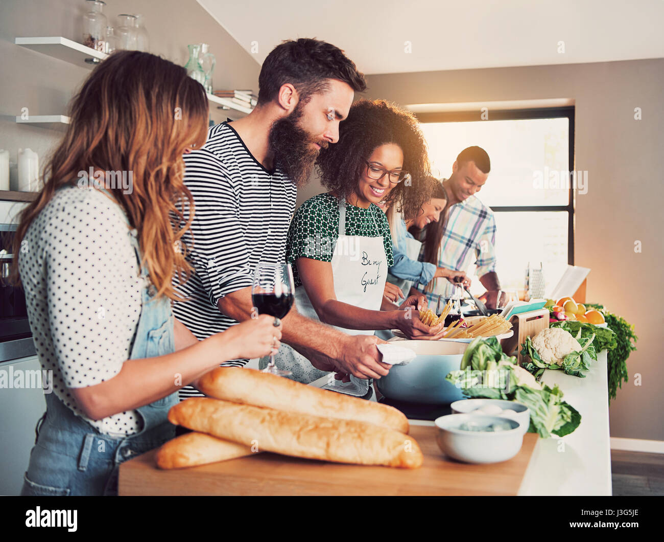 Grand groupe de six amis de préparer des aliments pour un cours de cuisine à table à la maison ou dans une petite école de cuisine Banque D'Images