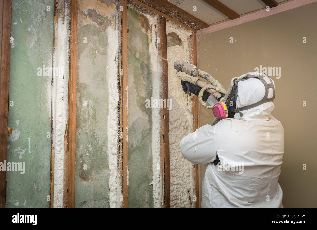 La pulvérisation de mousse à cellules ouvertes de travailleurs sur l'isolation des murs intérieurs de la maison Banque D'Images