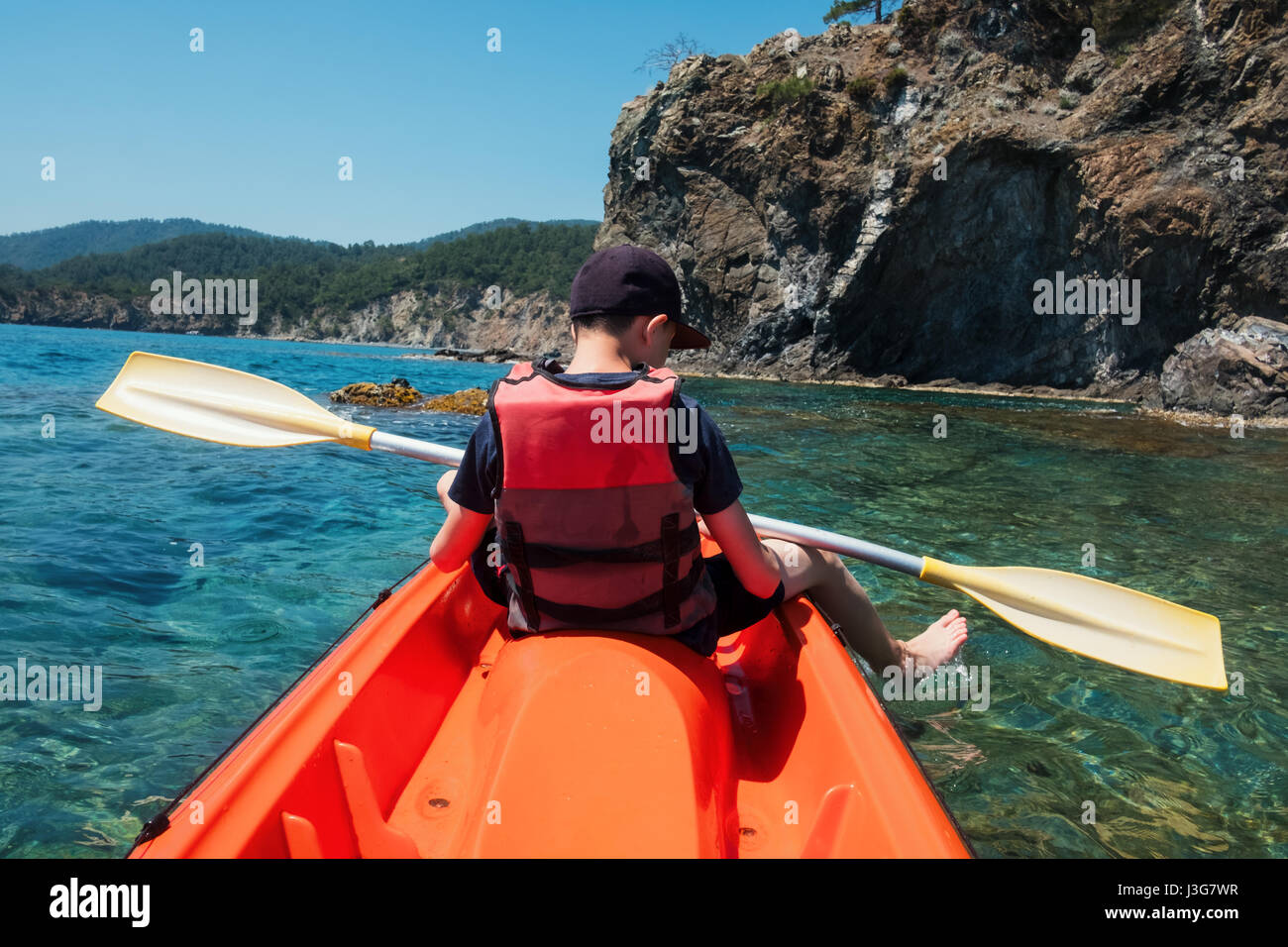 Garçon en veste de kayak sur l'orange. Journée ensoleillée sur la mer méditerranée. L'heure d'été Banque D'Images