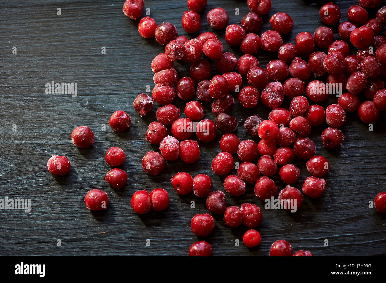 Beaucoup de cerises congelées sans bâtons sur un fond noir en bois.Des vitamines et une alimentation saine Banque D'Images