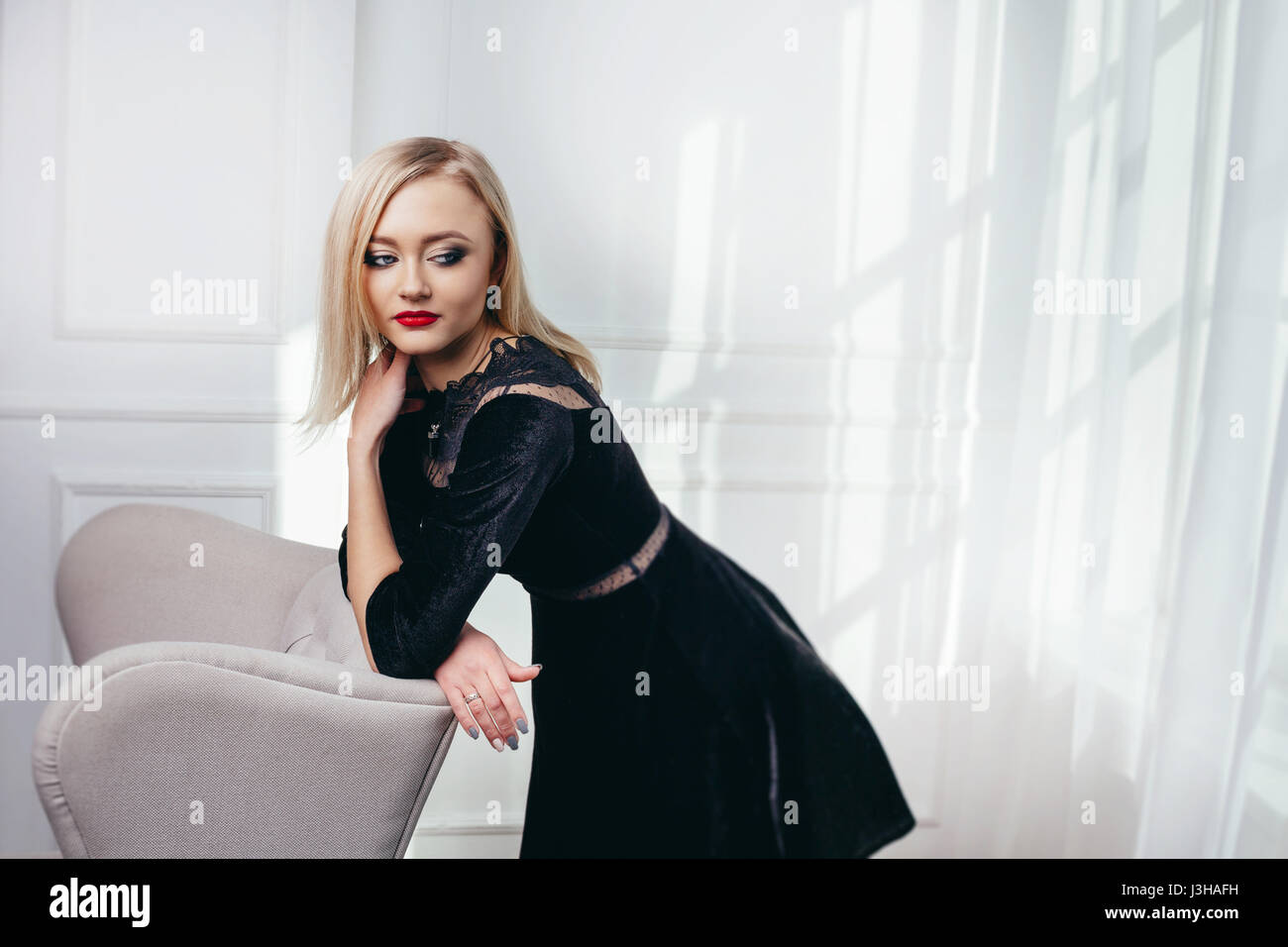 Portrait de jeune et belle fille en robe noire portant en studio. Banque D'Images