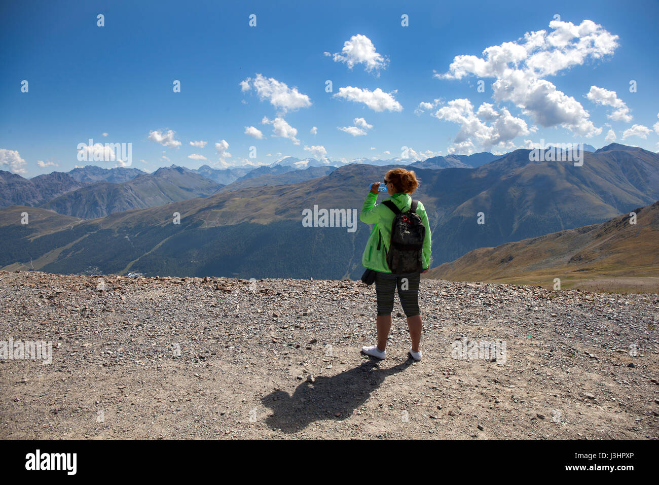 Femme hiker with backpack boire de l'eau et profiter d'une vue magnifique à partir d'un pic de haute montagne. Banque D'Images