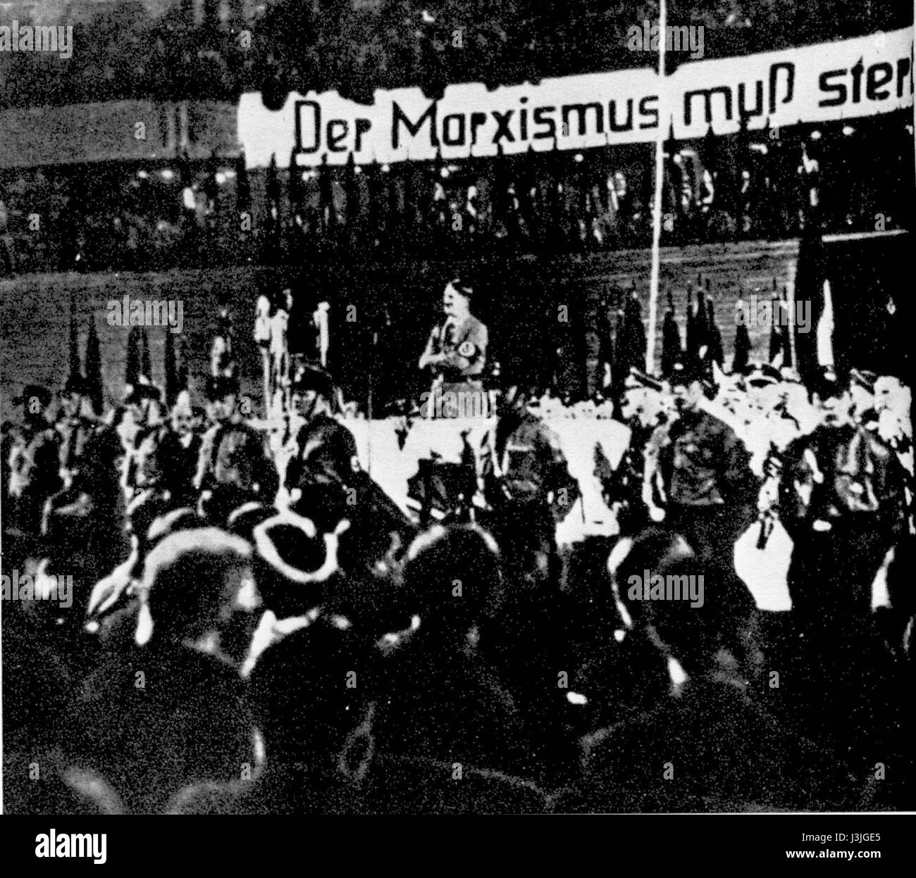 Une photographie historique d'Adolf Hitler parlant lors d'un rassemblement, illustrant l'intensité de ses discours et l'atmosphère de la propagande nazie. Cette image représente un moment clé de l'histoire du XXe siècle, capturant l'influence d'une figure politique majeure pendant la montée du régime nazi. Banque D'Images