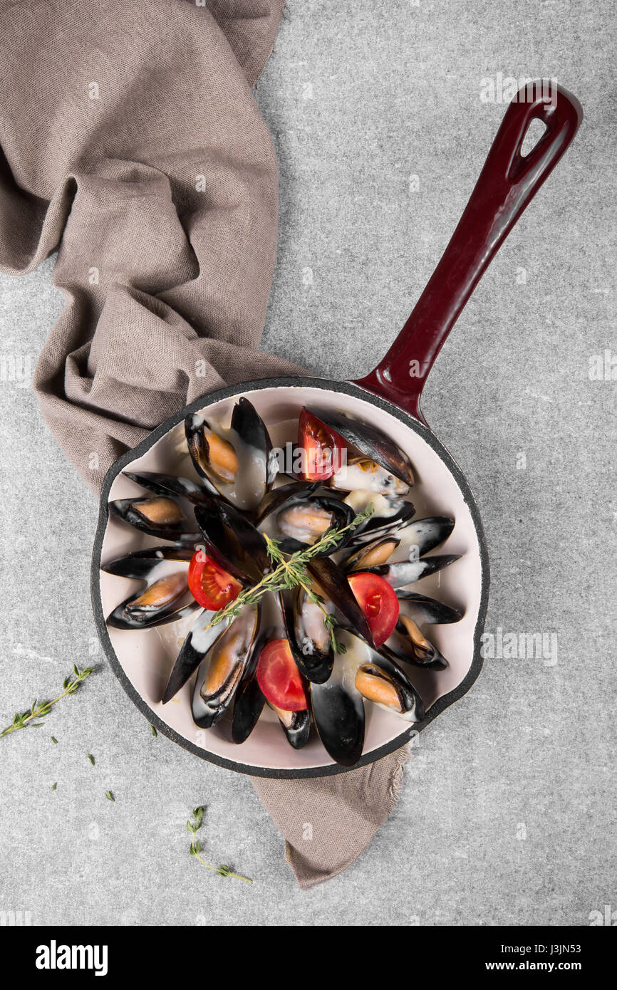 Les moules cuites à la poêle servi sur une serviette garnie de tomates et le thym. Les moules cuites à la vapeur dans une sauce au vin blanc. Banque D'Images