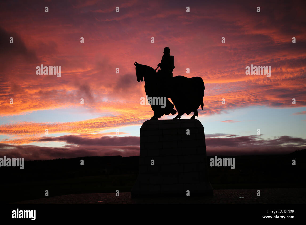 Le roi Robert Bruce le statue équestre, silhouetté contre un ciel de l'ouest rouge au coucher du soleil au National Trust Bannockburn Heritage Centre Banque D'Images