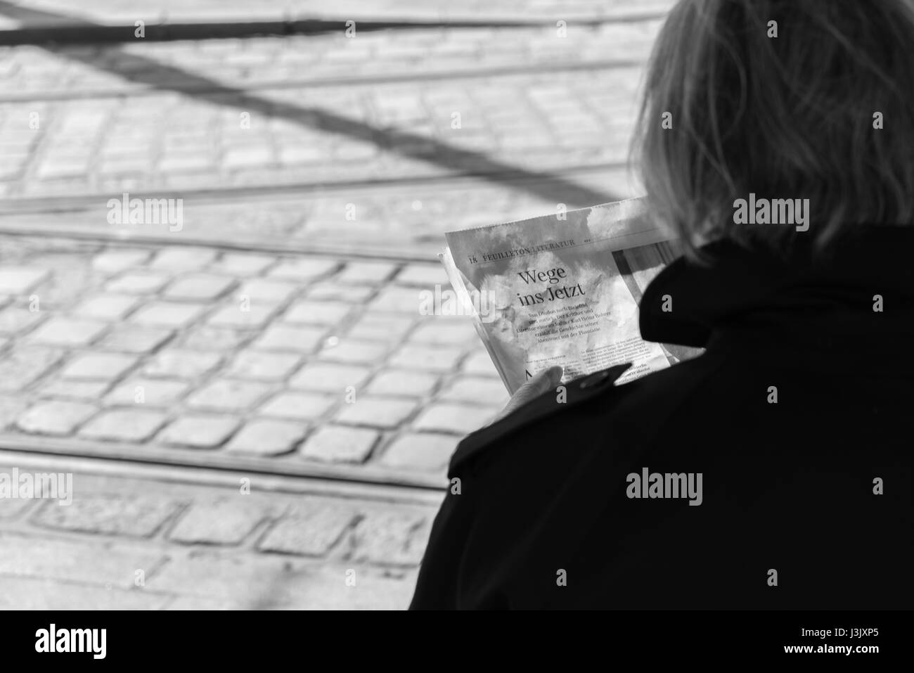 Vue sur l'épaule d'une femme plus âgée lisant un article sur les moyens en maintenant et certaines routes ferroviaires dans l'arrière-plan Banque D'Images