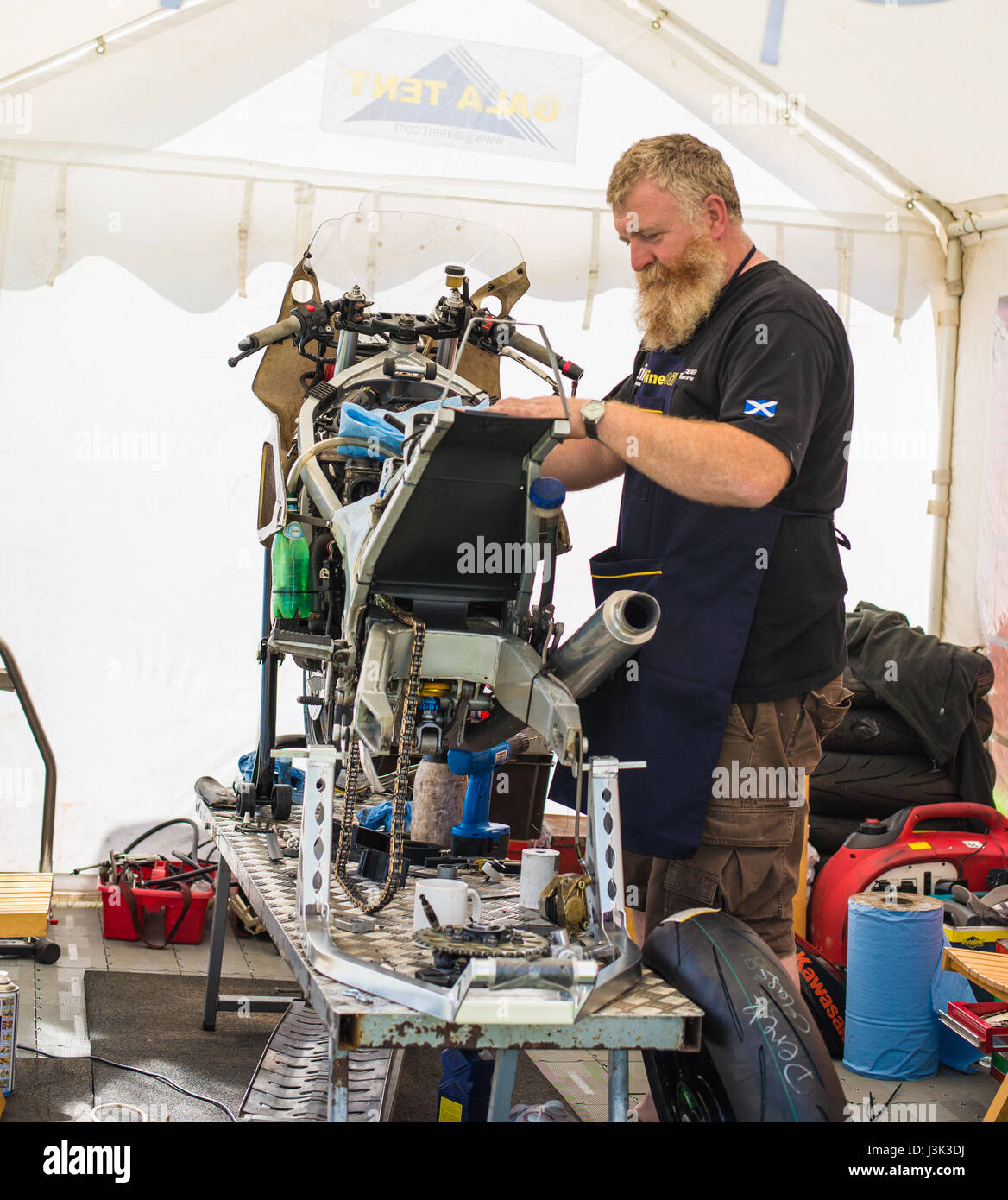 L'équipe écossaise tente au Manx Grand Prix, l'homme travaillant sur un vélo Banque D'Images