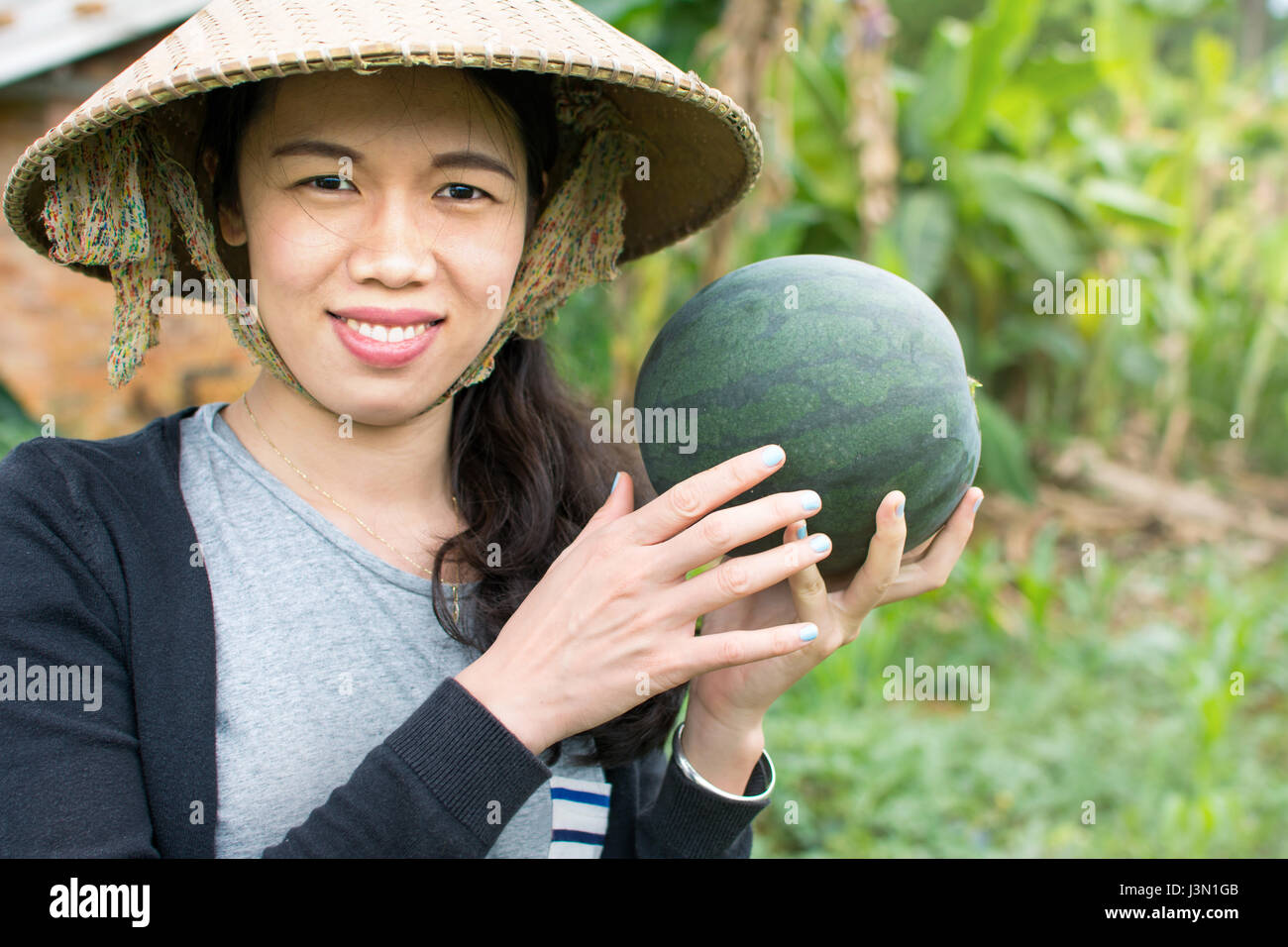 Female farmer holding fresh watermelon dans le domaine Banque D'Images