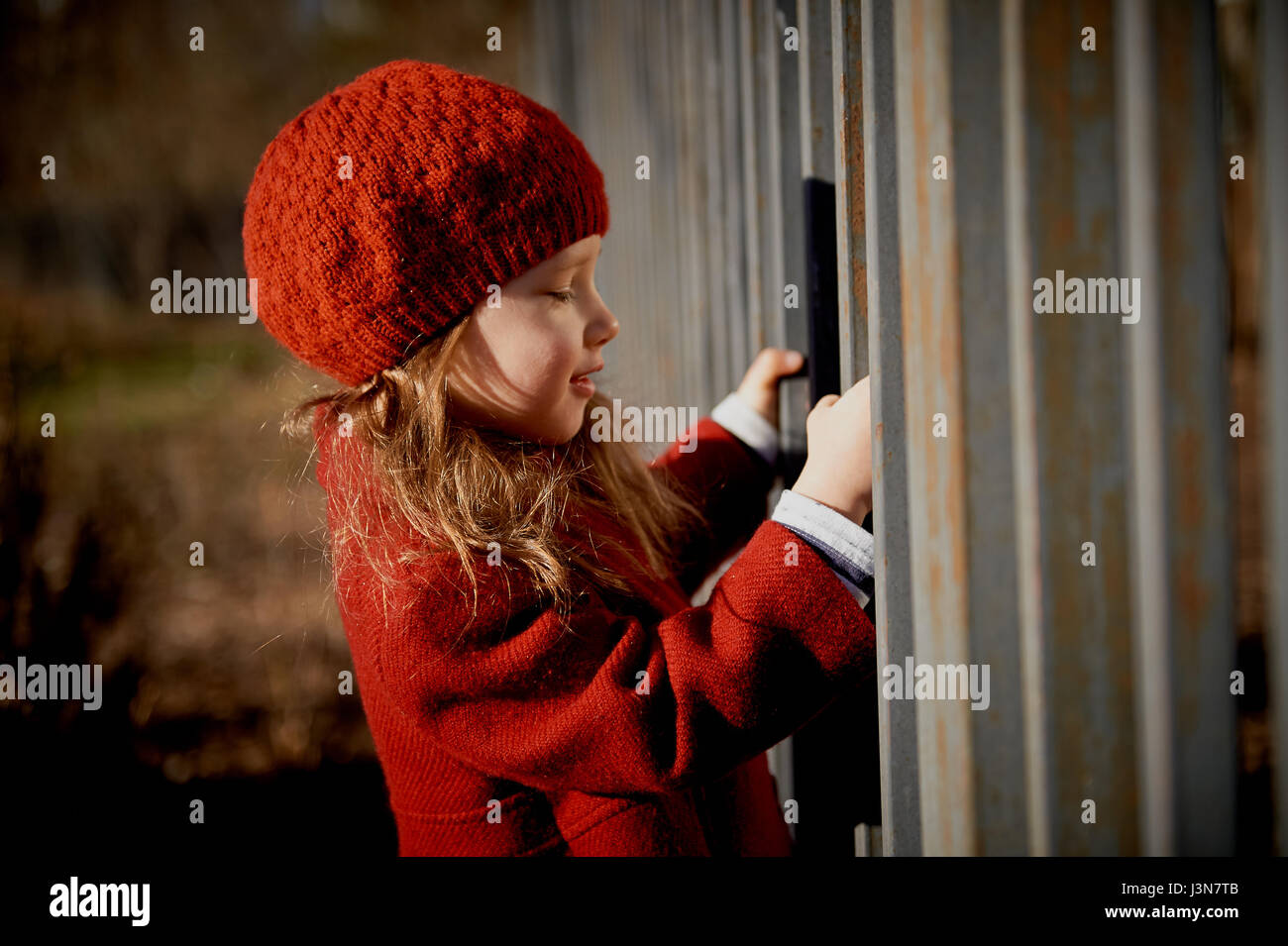 Bebe 3 Ans Avec Des Cheveux Longs Dans Un Beret Rouge Et Portes Manteau Sur La Rue Au Soleil Pres De La Cloture Photo Stock Alamy