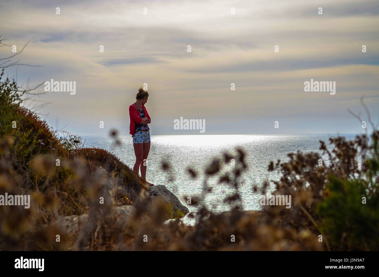 Jeune fille se tient seul avec armoiries croix par une mer solitaire Banque D'Images