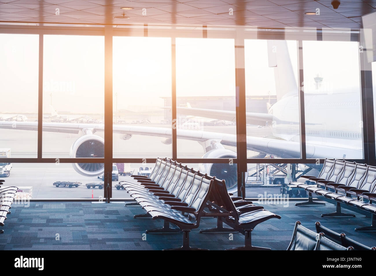L'aéroport d'embarquement vide salon avec rangées de sièges et des fenêtres avec la vue d'un gros aéronef prêt à voler Banque D'Images