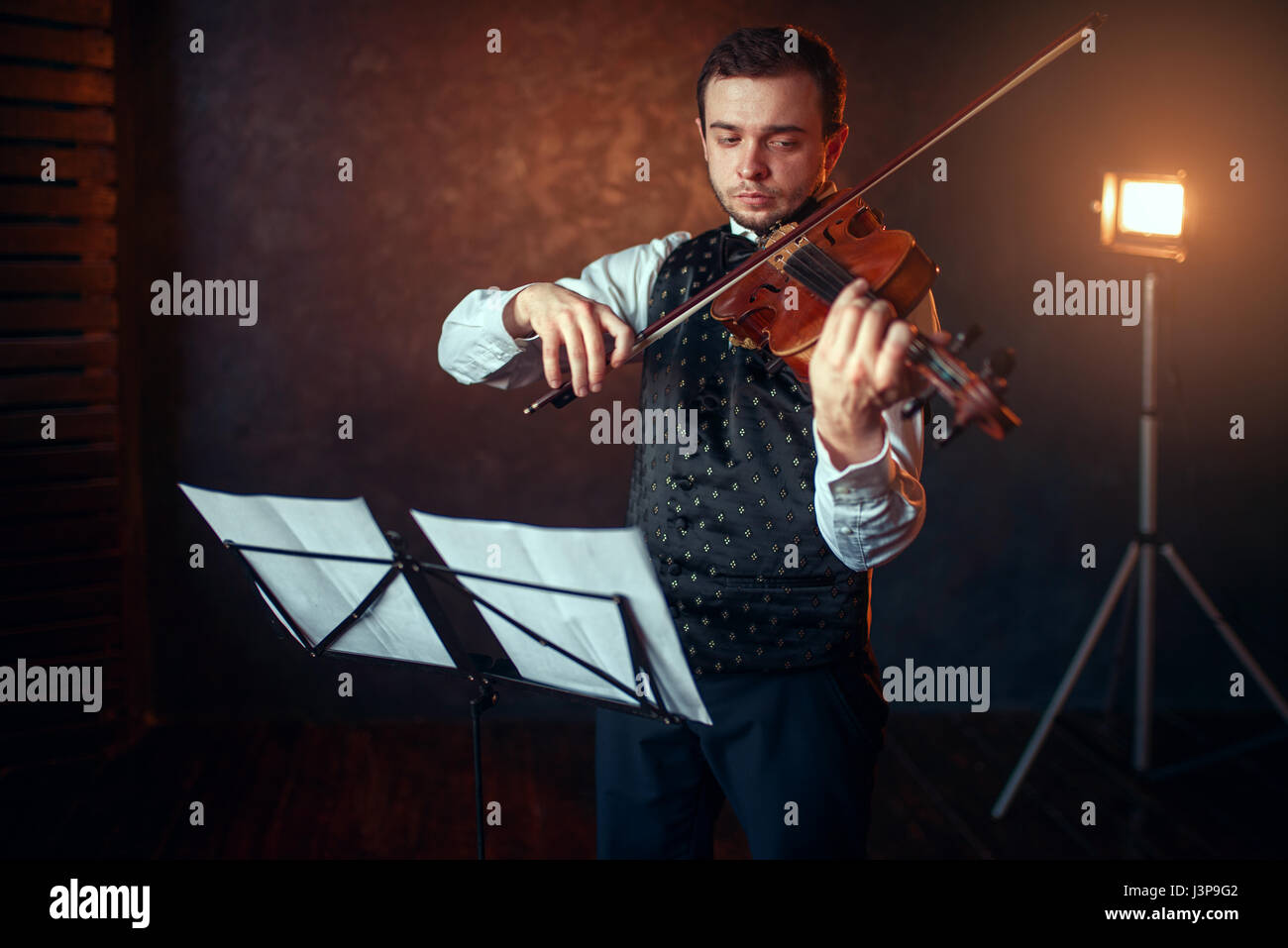 Portrait d'homme avec violon violoniste contre music stand. Fiddler homme avec instrument de musique jouant en studio, la formation de concert solo Banque D'Images