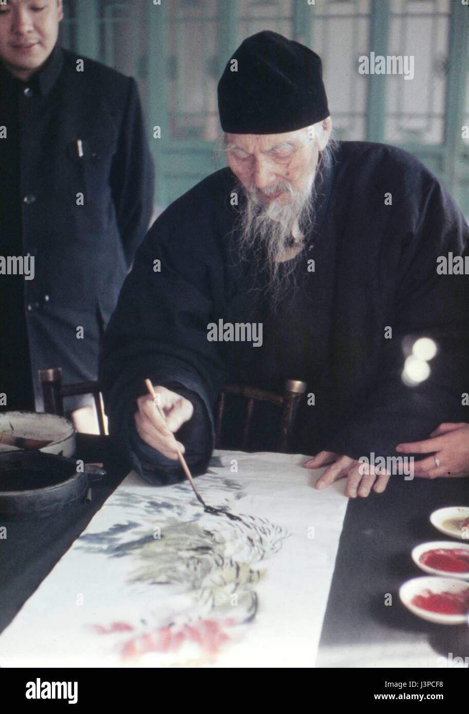 Qi Baishi peinture d'un défiler dans son atelier à Pékin, en 1957, quelques mois avant sa mort. Regardant par-dessus son épaule est son fils. Banque D'Images