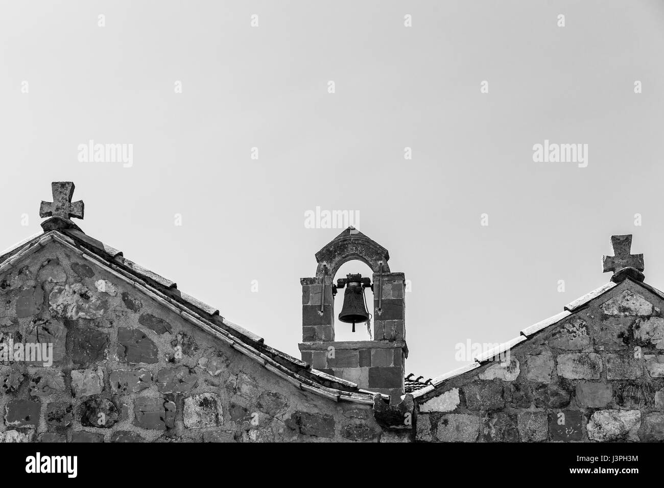 Un clocher capturé en monochrome vu entre deux toits sur l'île croate de Sipan. Banque D'Images