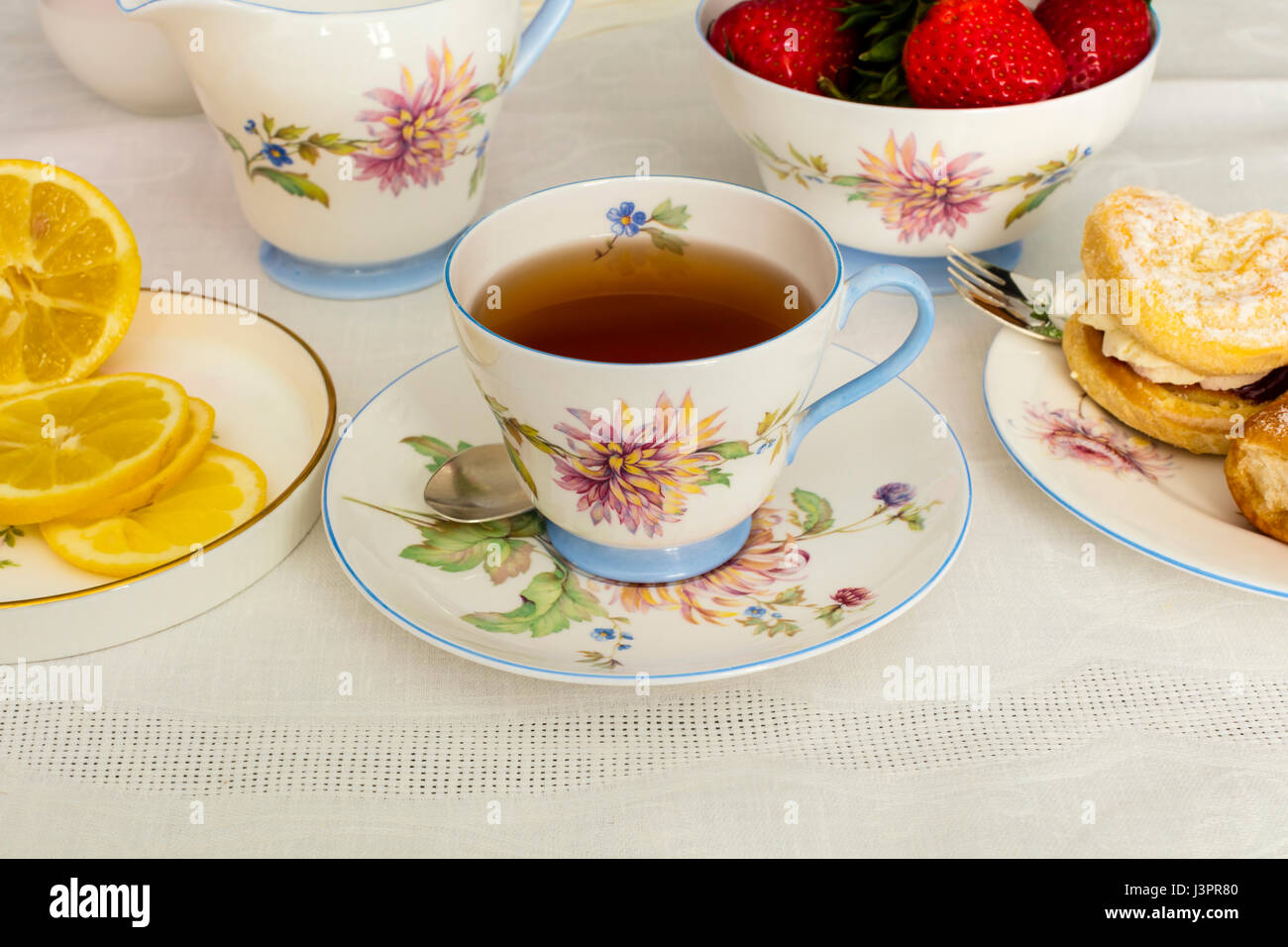 Tasse de thé servi dans une tasse de thé de Chine fine vintage avec des gâteaux à la crème. Banque D'Images