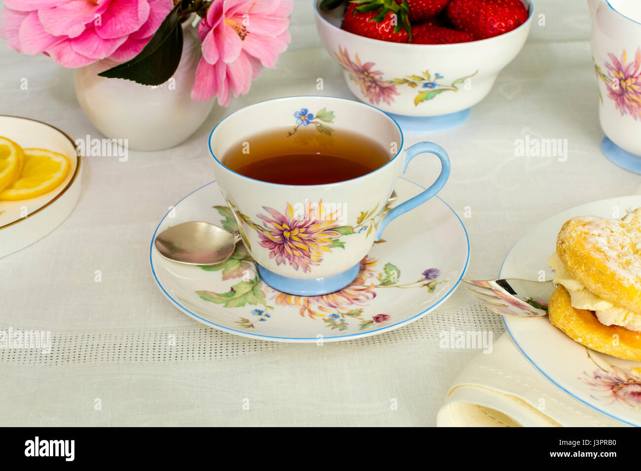 Tasse de thé servi dans une tasse de thé de Chine fine vintage avec des gâteaux à la crème. Banque D'Images
